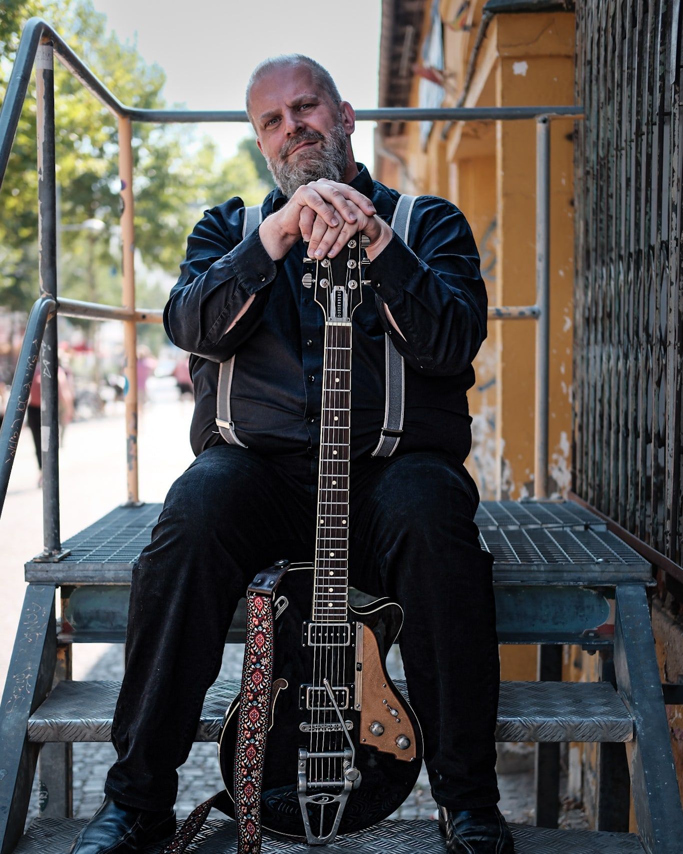 Knut Schfleck sitzt mit E-Gitarre auf einer Metalltreppe